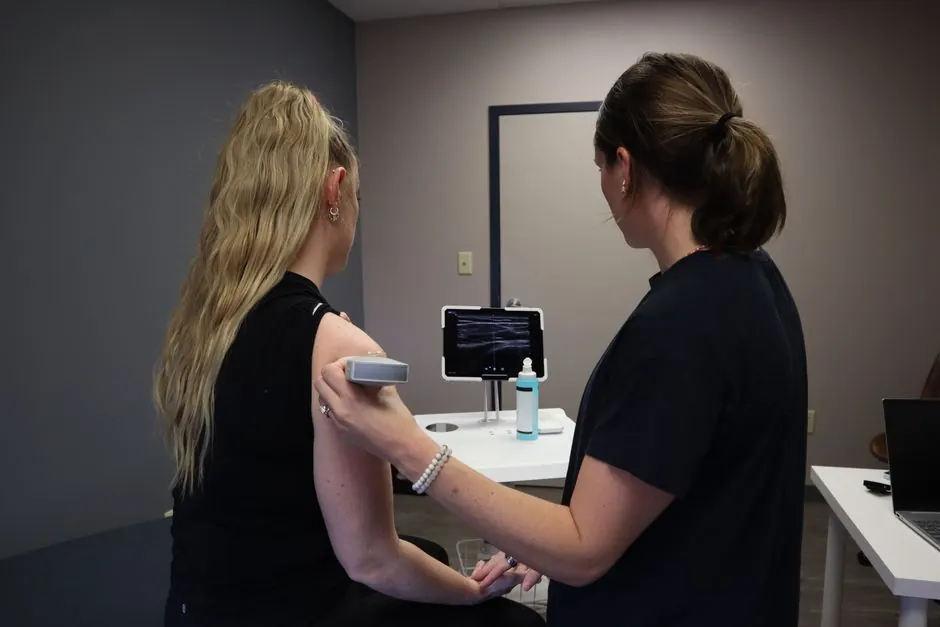 A nurse performs an ultrasound on a woman's shoulder, showcasing modern medical technology.